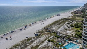 A beach with a pool area, a lifeguard tower, and a boardwalk.