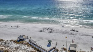 A beach with a lifeguard tower, a small building, and a wooden boardwalk.