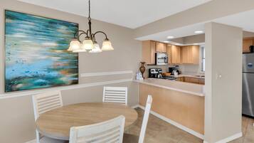 A modern kitchen with white cabinets, a central island, and a dining area with a round table and chairs.
