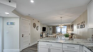 A spacious kitchen with white cabinetry, a marble countertop, and a dining area with a table and chairs.