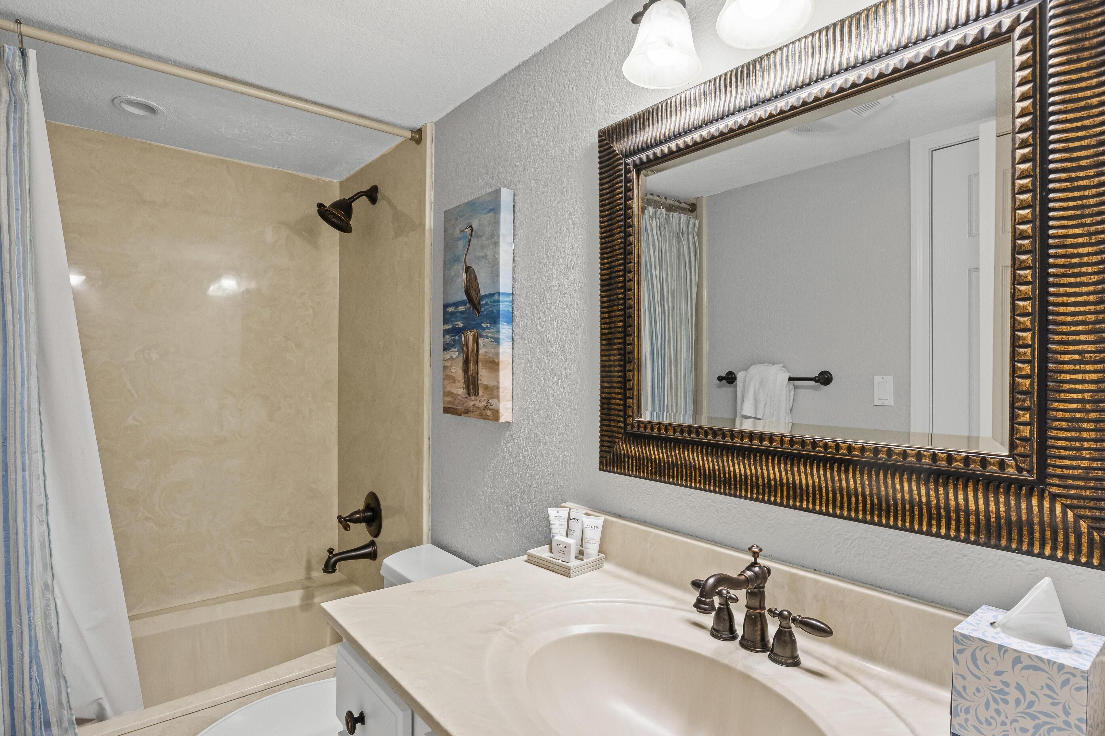A bathroom with a large mirror, a sink, a shower, and a towel rack.