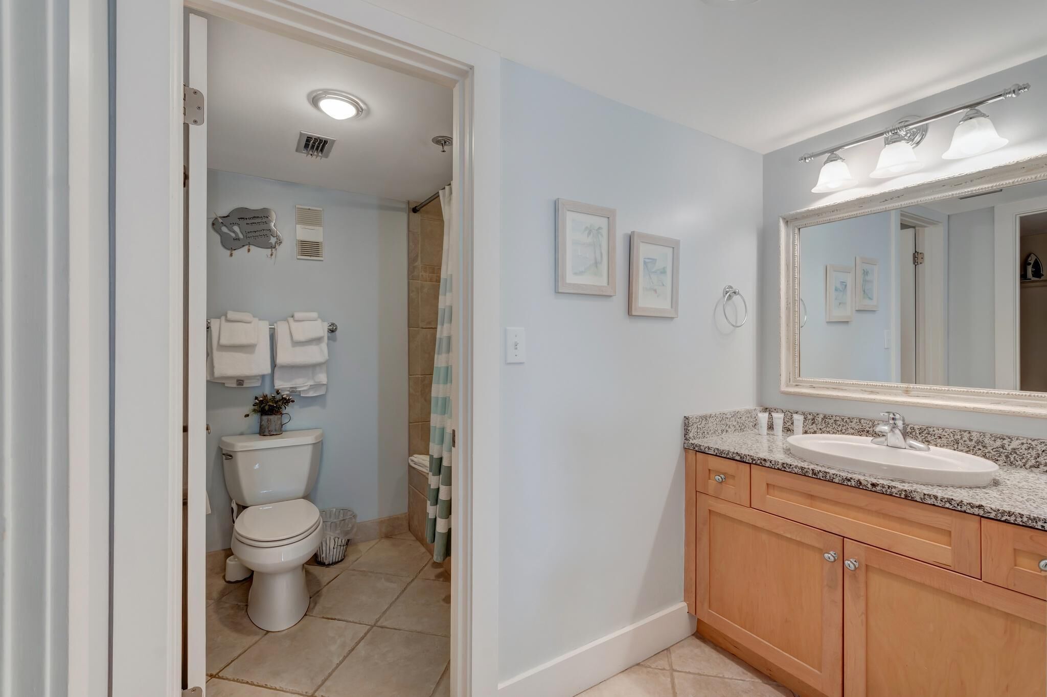 A bathroom with a toilet, sink, and mirror.