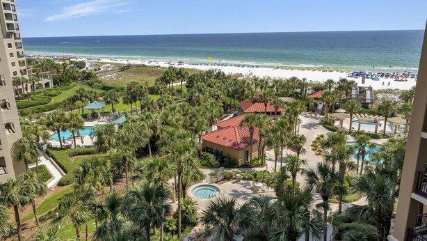 Un resort con piscina, palme e vista sulla spiaggia.