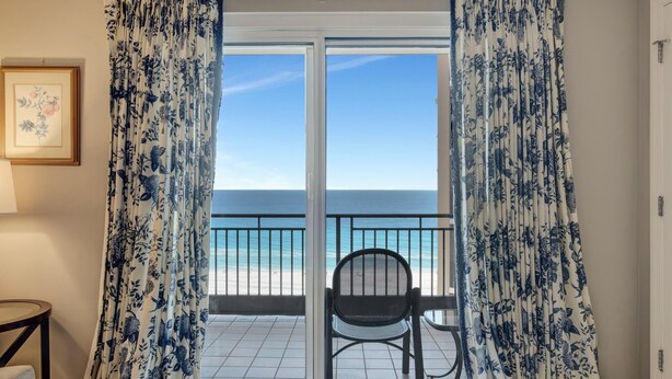 A balcony with a view of the beach, a chair, and a framed picture on the wall. - "Modern Elegance at Westwinds: Updated 1-Bedroom Condo on the 10th Floor!" at Sandestin Golf and Beach Resort! (Miramar Beach)