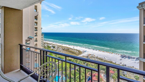 A balcony with a view of the beach and ocean.