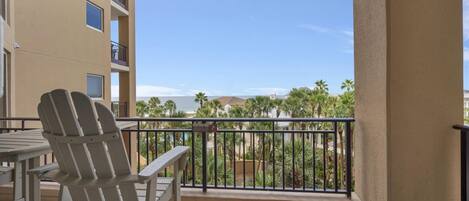 A balcony with a view of palm trees and a building in the distance.