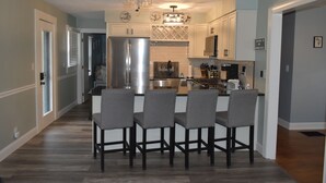 A modern kitchen with a central island, stainless steel appliances, and a ceiling fan.