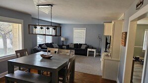 A modern living room with a dining area, a sofa set, and a chandelier.