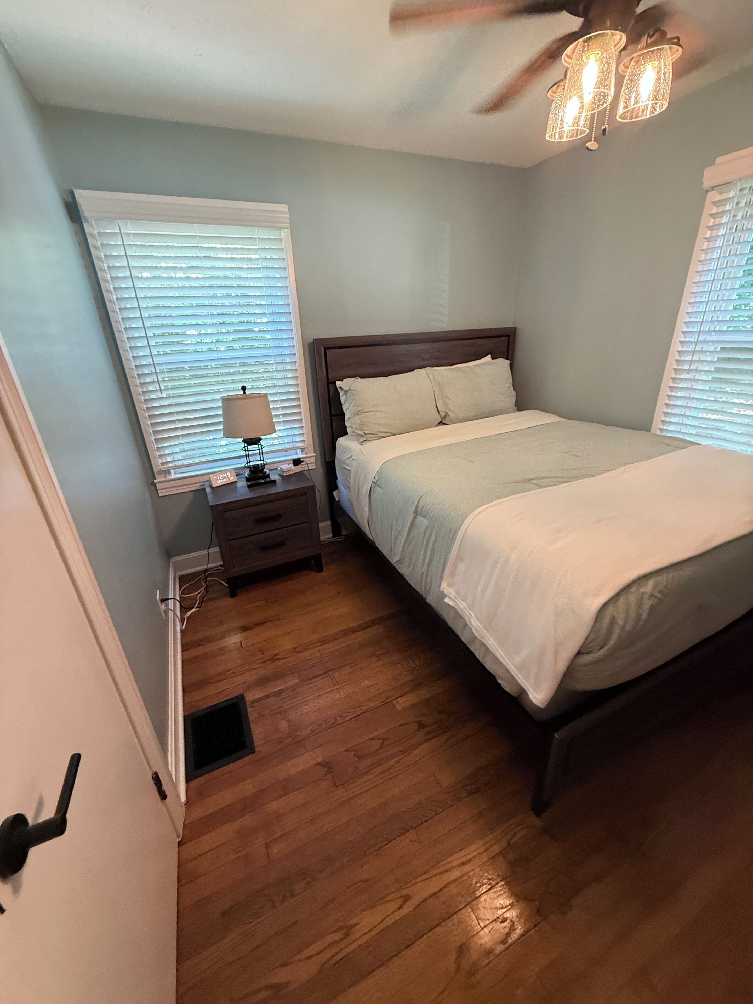Ein Schlafzimmer mit Bett, Nachttisch, Lampe und Deckenventilator.