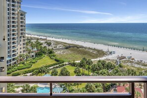 Un hotel moderno con vistas a una playa, piscina y zonas ajardinadas.