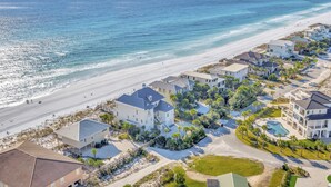 Un quartier résidentiel situé sur la côte, avec des propriétés en bord de mer, notamment des maisons dotées de grandes fenêtres et de balcons, ainsi qu’une piscine.