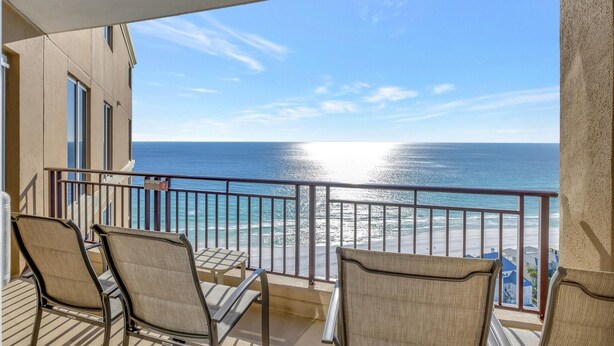 Un balcon avec des chaises donnant sur une plage et l’océan.