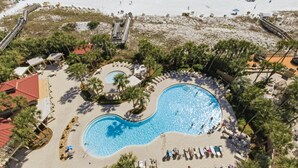 Un complejo turístico con una piscina grande, palmeras y acceso a la playa.