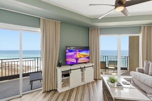 A living room with a TV, a balcony with a view of the ocean, and a ceiling fan. - "Beachfront Bliss: East-Facing 3-Bed, 3-Bath Corner Unit on the 9th Floor at Westwinds Condominium" at Sandestin Golf and Beach Resort! (Miramar Beach)