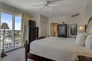 A hotel room with a large bed, a ceiling fan, a television, and a view of the city through large windows. - "Sunset Splendor: West-Facing 3-Bed, 3-Bath Oasis on the 9th Floor at Westwinds" at Sandestin Golf and Beach Resort! (Miramar Beach)