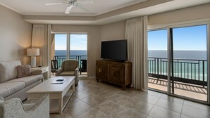 Un salon spacieux doté d’une grande télévision, de sièges confortables et d’un balcon offrant une vue sur l’océan.