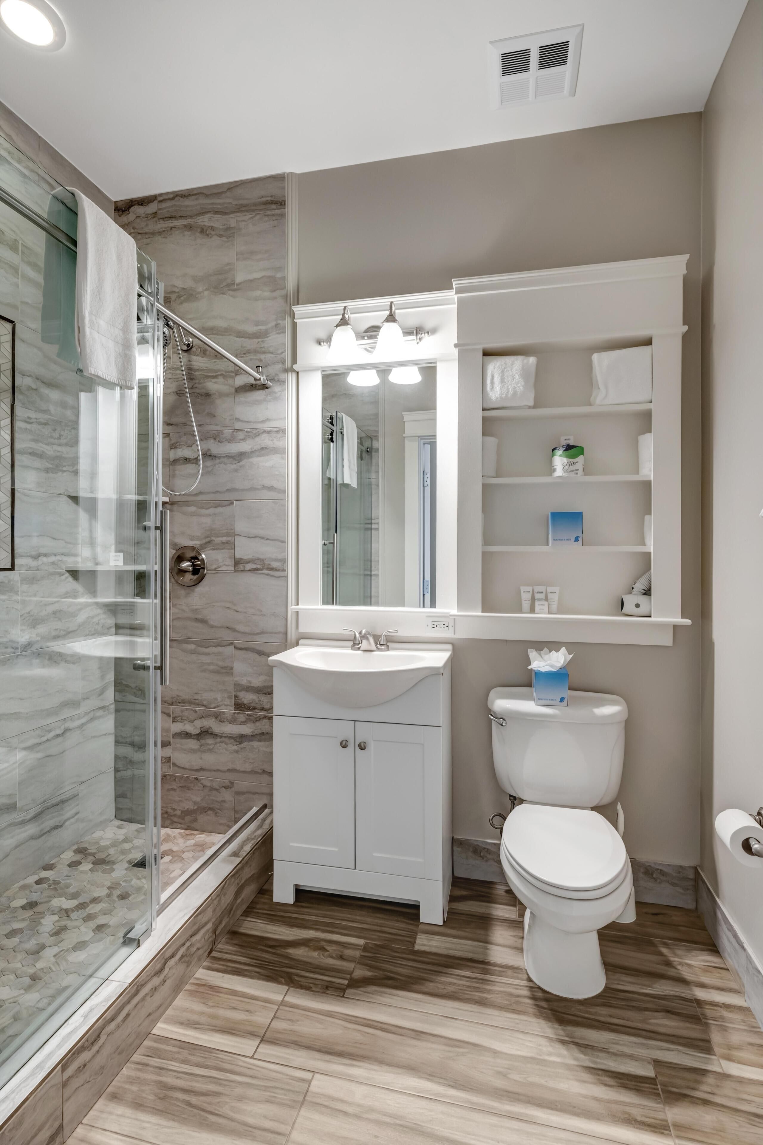 A modern bathroom with a glass shower enclosure, a white sink, and a toilet.