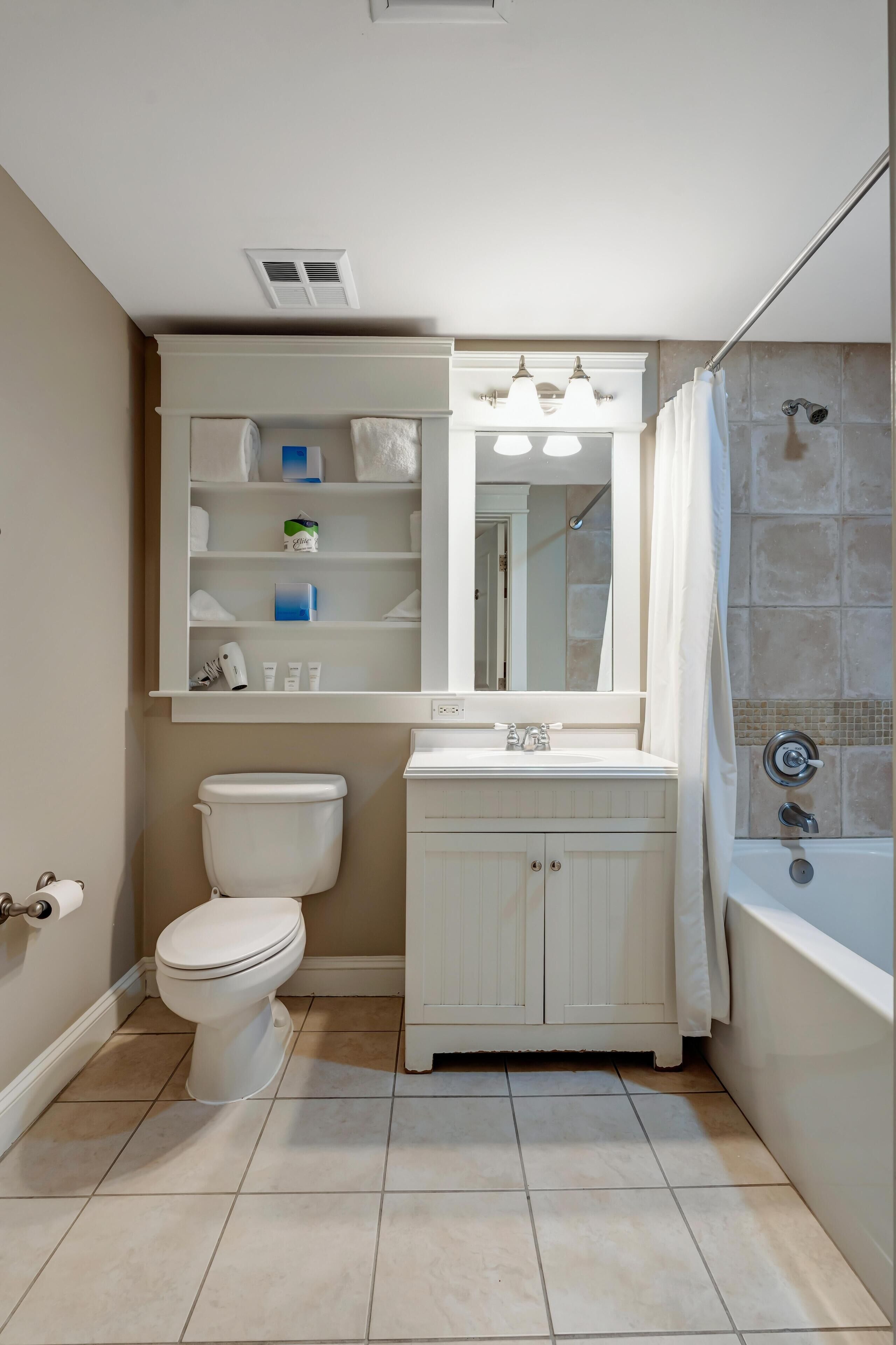 Une salle de bain comprenant des toilettes, un lavabo, un miroir et une douche.