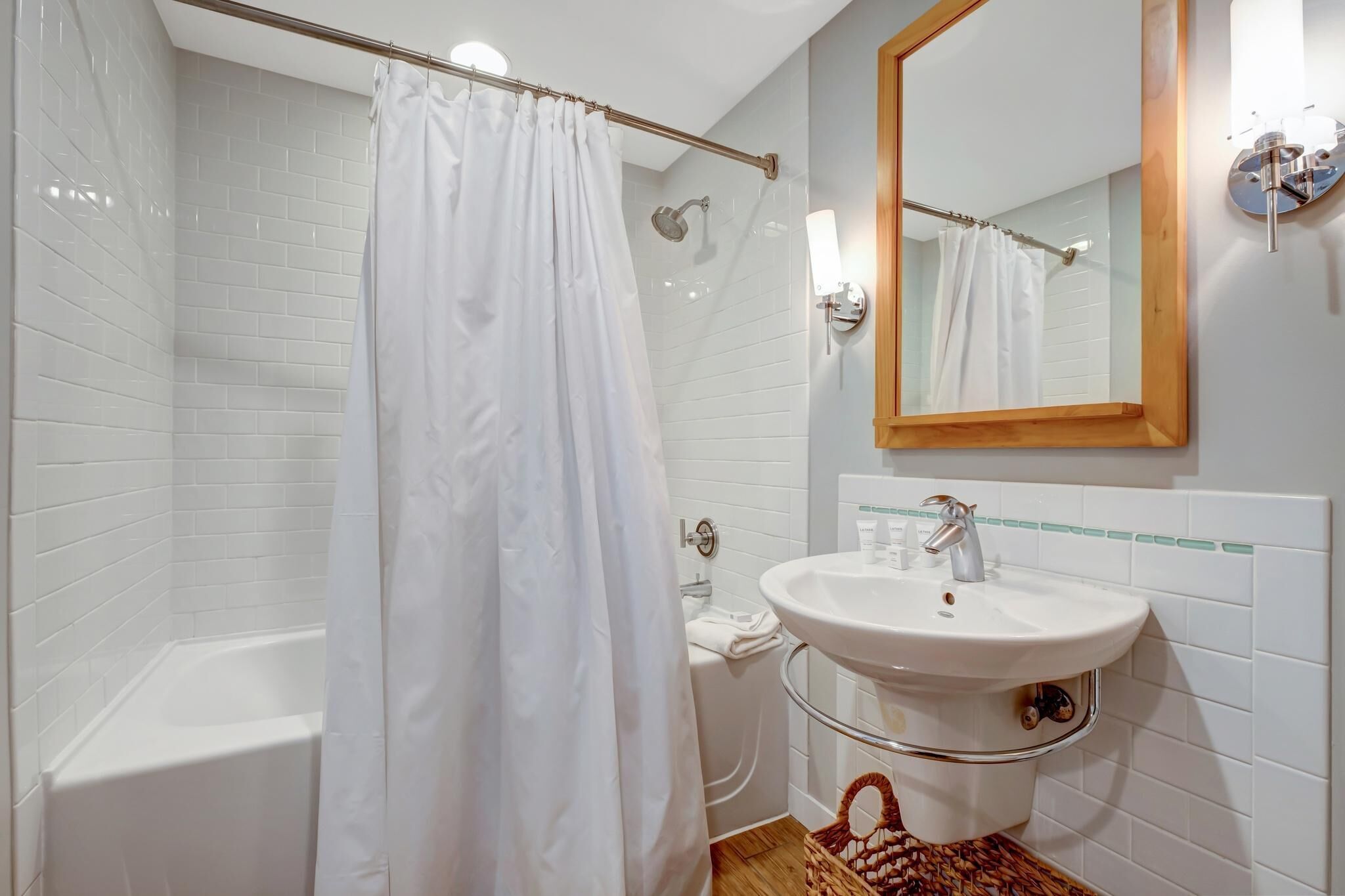 A bathroom with a bathtub, a white sink, and a mirror.