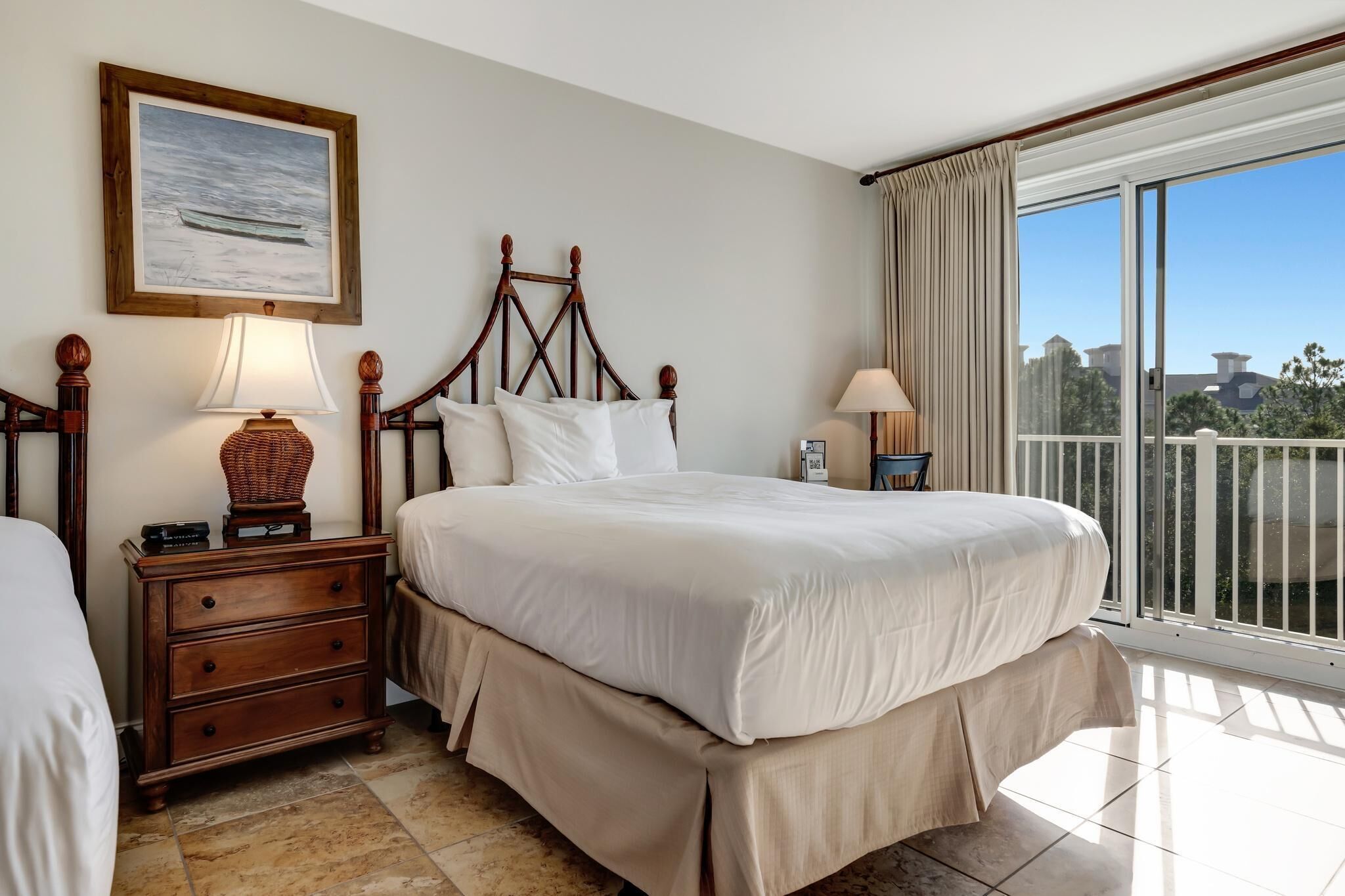 Une chambre d’hôtel avec un grand lit, une table de chevet avec une lampe, une commode et une fenêtre donnant sur l’extérieur.
