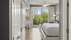 Ein Schlafzimmer mit einem Bett, einem Schreibtisch und Blick auf Grünflächen.