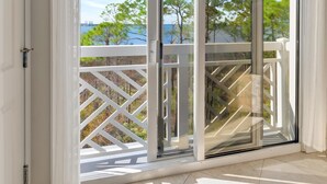 A balcony with a view of trees and a body of water.