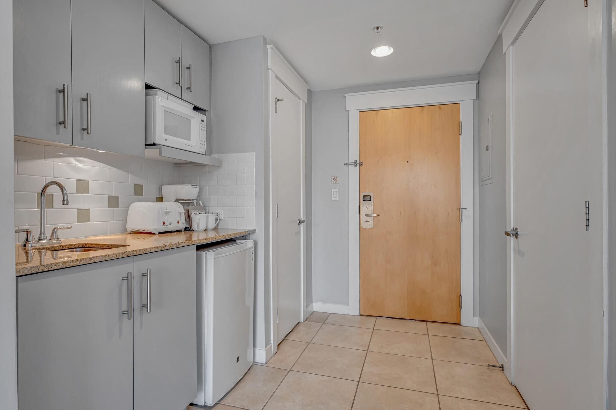 A modern kitchen with grey cabinets, a microwave, a toaster, and a sink.