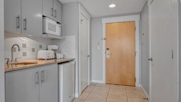 A modern kitchen with grey cabinets, a microwave, a toaster, and a sink.