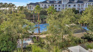 A large building with a swimming pool surrounded by lush greenery. - Serene Choctawhatchee Bay Views from 4th Floor One Bedroom, Two Bathroom Condo with Large Private Balcony at Sandestin Golf and Beach Resort! (Miramar Beach)
