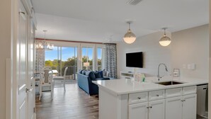Una cocina moderna con armarios blancos, una isla central y un comedor con mesa y sillas.