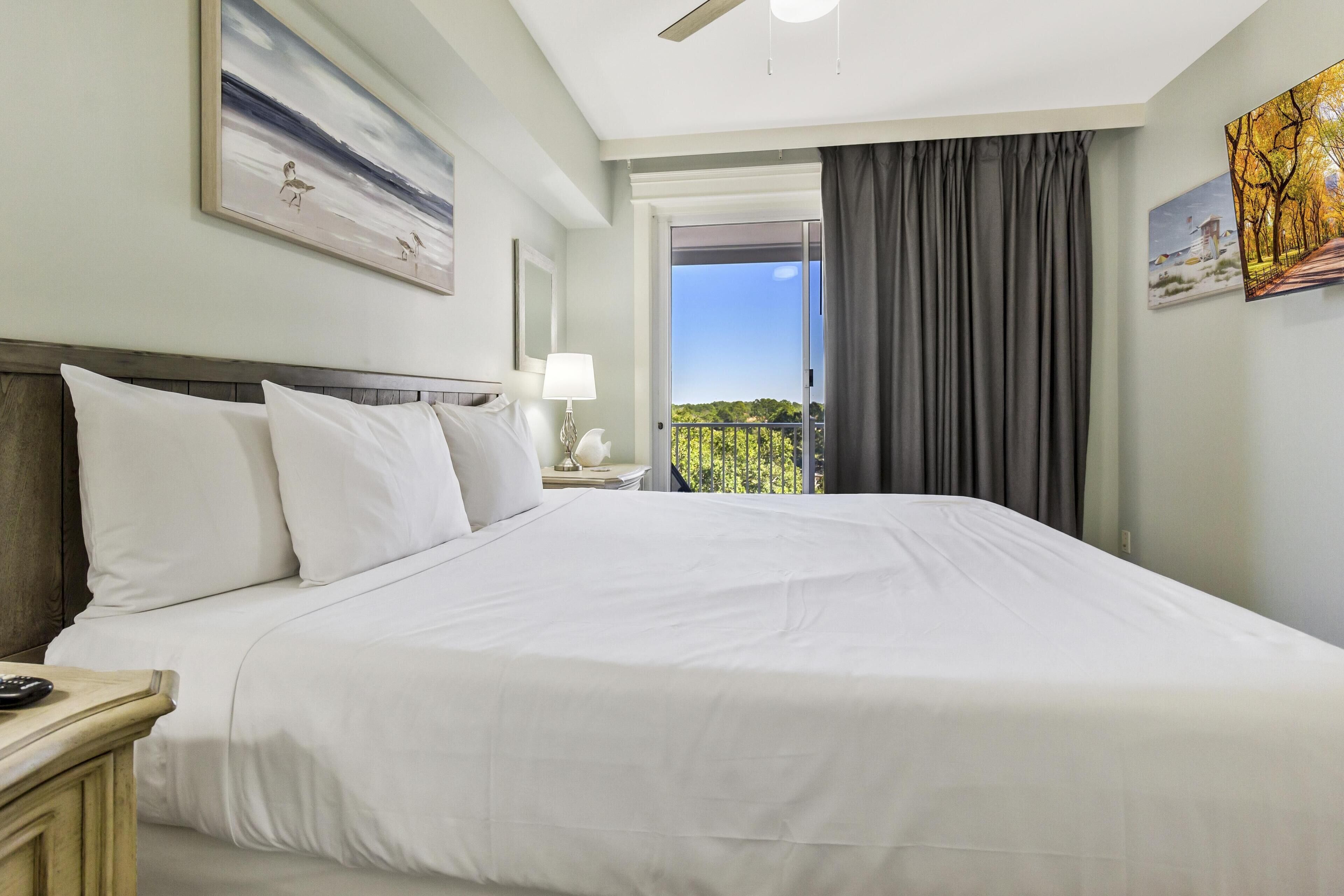 A hotel room with a large bed, a nightstand, a lamp, and a painting on the wall.