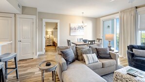 Ein modernes Wohnzimmer mit einer Eckcouch, einem Esstisch und einer Küche im Hintergrund.