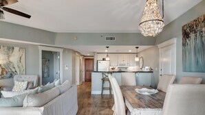 Un salón espacioso con un sofá grande, una mesa de comedor y una cocina al fondo.