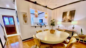 A dining area with a round table, chairs, a small plant, and pendant lighting. - Townhouse in the West End steps from everything! Main St, Falls Park, Baseball  (Greenville)