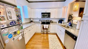 A modern kitchen with white cabinets, stainless steel appliances, and a wooden floor. - Townhouse in the West End steps from everything! Main St, Falls Park, Baseball  (Greenville)