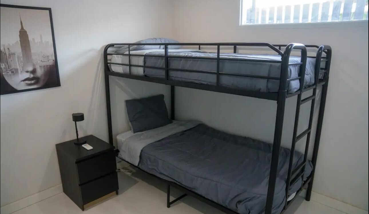 A bunk bed room with a small bedside table and a framed picture on the wall.