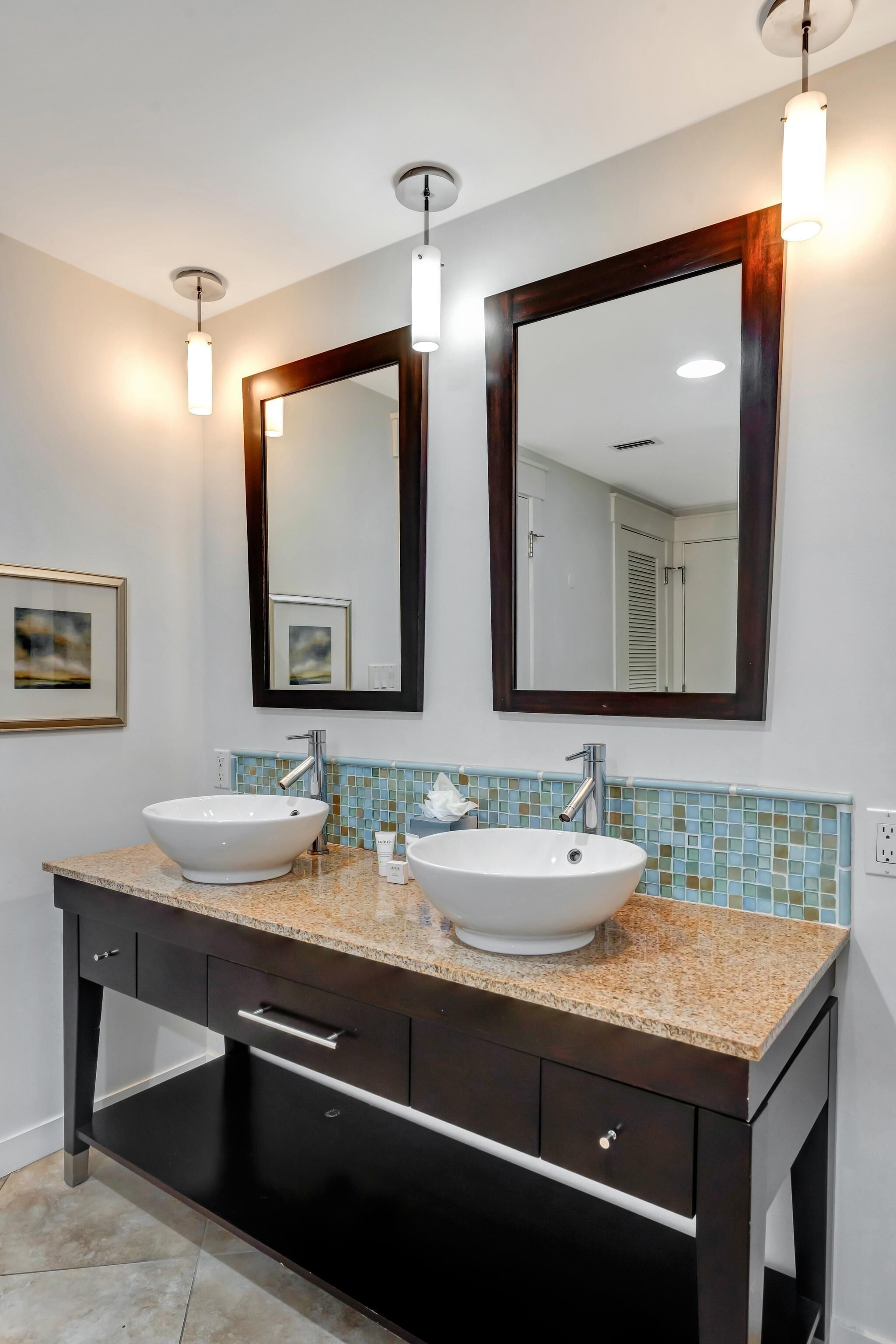 A bathroom with two sinks, a large mirror, and a tiled backsplash.