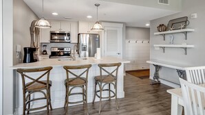 A modern kitchen with white cabinetry, stainless steel appliances, and a central island with bar stools.