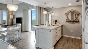 A modern kitchen with a central island, pendant lighting, and a large mirror.
