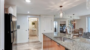 A modern kitchen with granite countertops, stainless steel appliances, and a dining area with wooden chairs.
