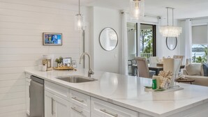 Una cocina moderna con una isla grande, electrodomésticos de acero inoxidable e iluminación colgante.
