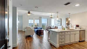 Een ruime woonkamer met een grote bank, een eettafel en een keuken met een kookeiland.