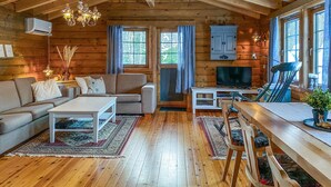 Ein gemütliches Blockhaus-Interieur mit Sofa, Couchtisch, Esstisch und Stühlen.