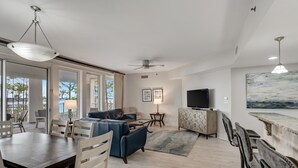Un amplio salón con mesa de comedor, sofá azul y televisor sobre un mueble.