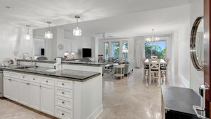 A spacious kitchen with a large island, white cabinetry, and pendant lighting.