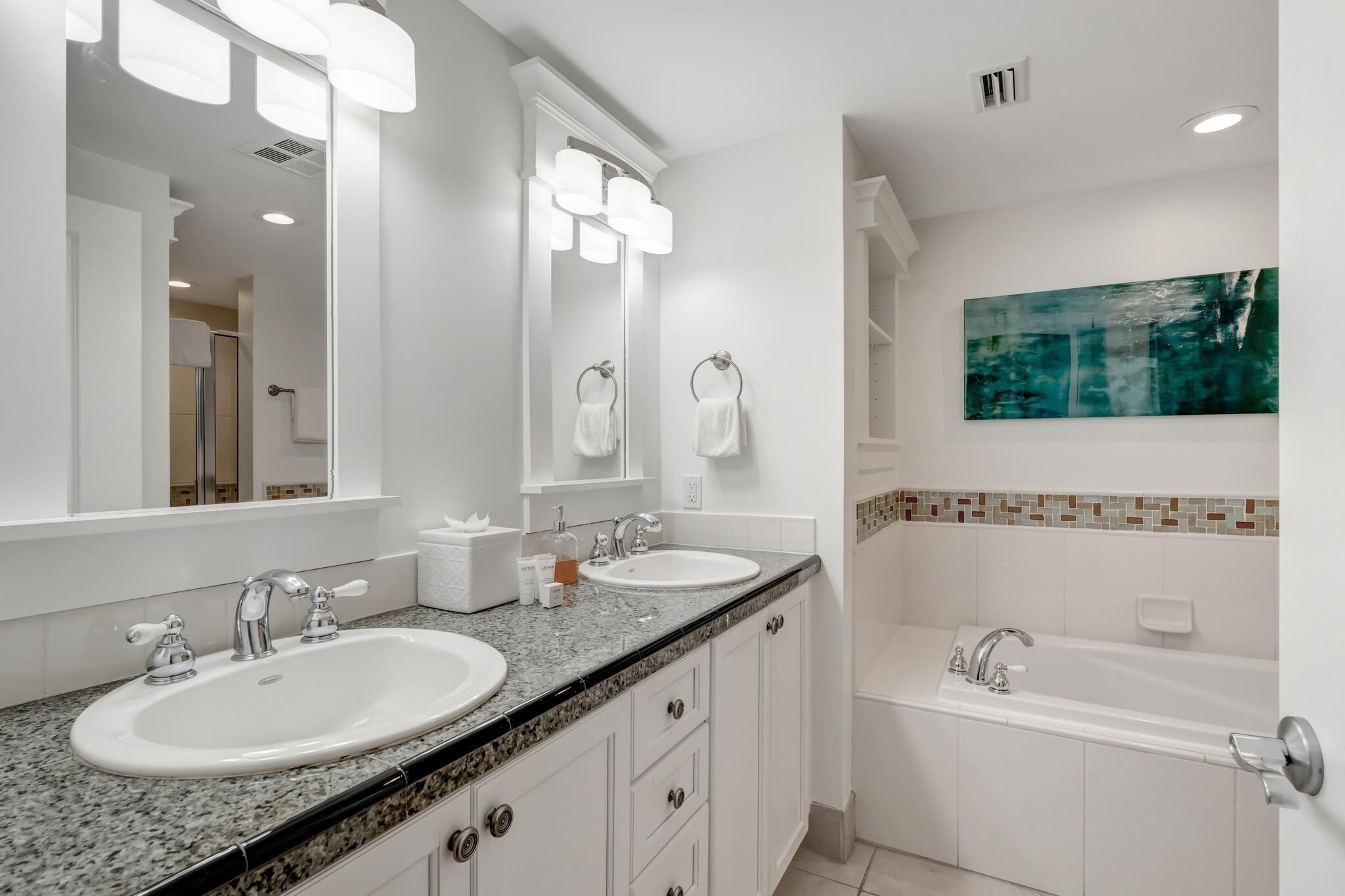 Un baño moderno con dos lavamanos, un espejo grande y una bañera.