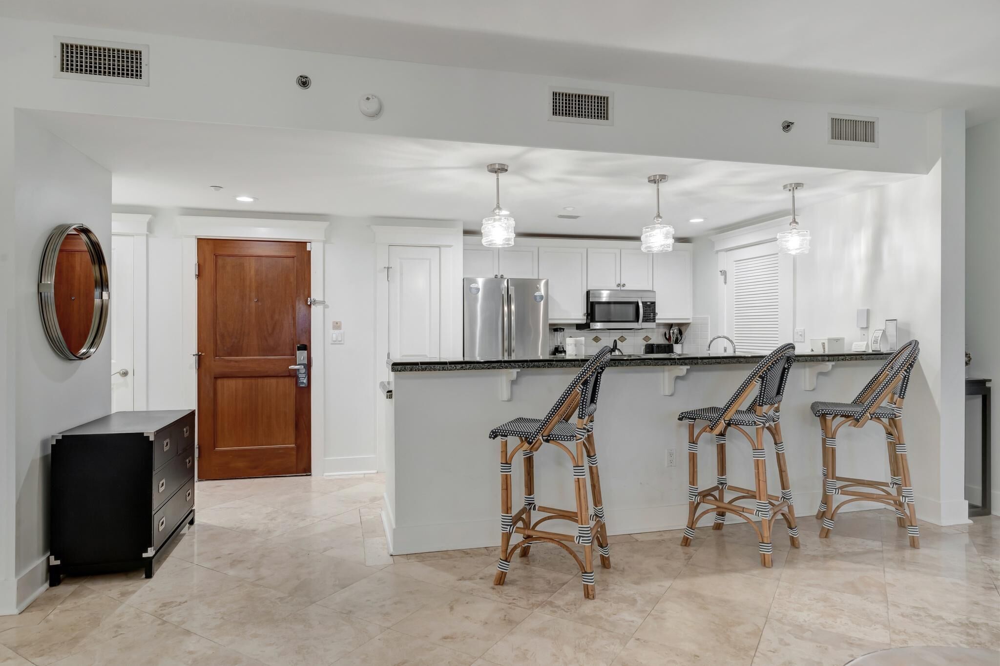 A modern kitchen with white cabinets, stainless steel appliances, and a central island with bar stools.