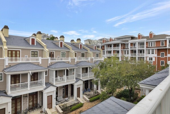 A row of townhouses with attached porches, brick chimneys, and white railings.