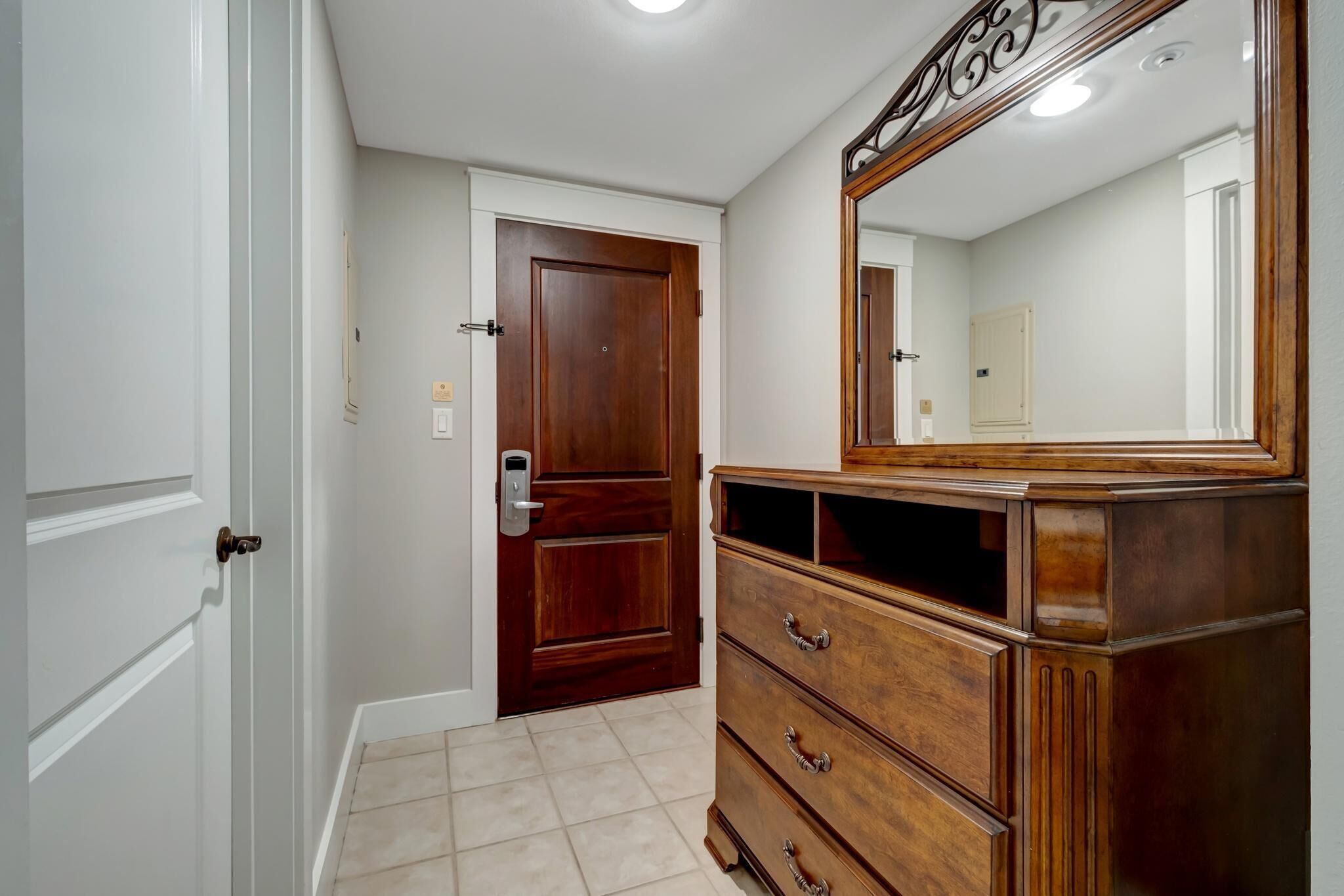 Una habitación con una puerta de madera, un aparador con cajones y un espejo.