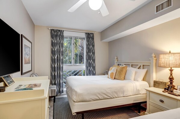 A hotel room with a bed, bedside table, lamp, and a window with curtains.